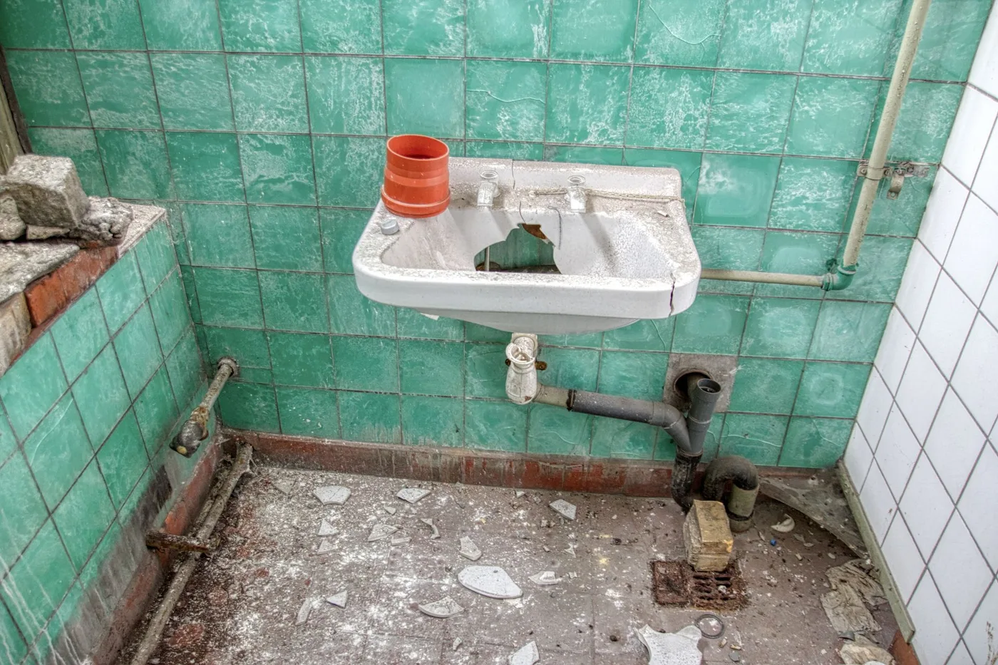 Tadilat öncesi sökülmüş banyo: kırık lavabo, paslı borular ve dökülen fayanslar